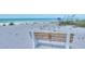 Relaxing beach scene with a wooden bench overlooking the clear ocean waters and vibrant beachgoers enjoying the sun at 4307 Gulf Dr # 208, Holmes Beach, FL 34217