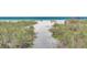 Scenic sandy path leading to a pristine beach with clear turquoise water and a comfortable bench at 4307 Gulf Dr # 208, Holmes Beach, FL 34217