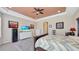 Bright primary bedroom featuring a decorative ceiling, ceiling fan, television, and a view to an ensuite at 5718 Westhaven Cv, Bradenton, FL 34203