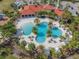 Overhead view of a community pool and clubhouse with palm trees, lounge chairs and cabanas surrounded by green space at 5821 Hevena Ct, Palmetto, FL 34221