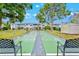 Community shuffleboard court framed by green grass, mature trees and black benches, offering recreational opportunities at 5855 Palm Ln # B21, Bradenton, FL 34207