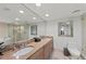 Bright bathroom features a large mirror over double sinks and a shower and separate soaking tub at 6500 Sunset Way # 311, St Pete Beach, FL 33706