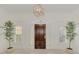 Elegant foyer with a dark wood door, transom window, sidelights and potted trees at 67 Sugar Mill Dr, Osprey, FL 34229