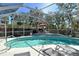 Gorgeous screened-in pool with blue tile accents and poolside lounge chairs at 746 Plymouth St, Sarasota, FL 34242