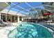 Enclosed pool with a tiled deck, multiple lounge chairs and an umbrella for shade on a sunny day at 746 Plymouth St, Sarasota, FL 34242