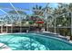 The crystal-clear screened-in pool has a tiled deck, multiple lounge chairs and an umbrella for shade at 746 Plymouth St, Sarasota, FL 34242