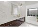 Modern bathroom with marble accent wall, dark wood vanity, decorative lighting and a soaking tub at 8487 Lindrick Ln, Bradenton, FL 34202