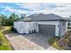 Side angle of a home showcasing a two car garage and beautiful brick paver driveway with neatly manicured landscaping at 8487 Lindrick Ln, Bradenton, FL 34202