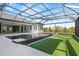 View of the screened-in pool with its sleek, modern tile and well-manicured artificial lawn, great for enjoyment all year round at 8487 Lindrick Ln, Bradenton, FL 34202