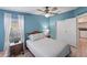 Tranquil bedroom featuring blue walls, natural light, and a comfortable queen-sized bed with a ceiling fan at 8536 Countess Avenue Cir, Palmetto, FL 34221