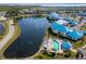 Stunning aerial view of condos by a tranquil pond, and a sparkling blue pool with palm trees and lounge chairs at 866 Audubon Dr, Bradenton, FL 34209