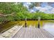 Wooden dock featuring sturdy pillars, providing access to tranquil waters surrounded by lush greenery at 866 Audubon Dr, Bradenton, FL 34209