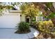 Front entrance of the home with the driveway, a welcoming walkway, and beautiful landscaping at 9590 Knightsbridge Cir, Sarasota, FL 34238