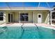 Rear view of the light green home featuring patio and pool with pool-side tiled border at 9590 Knightsbridge Cir, Sarasota, FL 34238