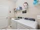 Laundry room with a white washer and dryer, a sink, storage shelves, and a white door at 15607 White Linen Dr, Lakewood Ranch, FL 34211