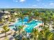 Aerial view of large community pool with palm trees, surrounded by lounge chairs and nearby community buildings at 17522 Northwood Pl, Bradenton, FL 34202