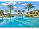 Eye-level view of a community pool with palm trees and lounge chairs near a lake at 17522 Northwood Pl, Bradenton, FL 34202