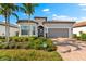 Charming home featuring lush landscaping, a brick driveway, and a two-car garage at 17522 Northwood Pl, Bradenton, FL 34202