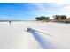 An expansive white sand beach under a sunny blue sky offers a peaceful setting for a relaxing day by the ocean at 310 Magnolia Ave, Anna Maria, FL 34216
