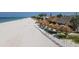 An aerial view of a vibrant beach lined with tiki umbrellas and huts, showcasing the lively atmosphere and inviting shoreline at 310 Magnolia Ave, Anna Maria, FL 34216