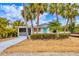 Charming single-story home with a vibrant blue door and well-maintained landscaping at 310 Magnolia Ave, Anna Maria, FL 34216