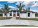 Beautiful home featuring a bright red double door, black window trim, and lush landscaping at 3188 Tropicaire Blvd, North Port, FL 34286