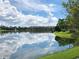 Scenic lake reflecting apartment complex and blue sky with fluffy white clouds at 3528 Lake Bayshore Dr # K-115, Bradenton, FL 34205