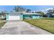 Charming turquoise home with a well-manicured lawn and long driveway on a sunny day at 400 Dona Dr, Nokomis, FL 34275