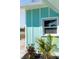 Close up of home exterior featuring plants and a white frame window on the light blue siding at 400 Dona Dr, Nokomis, FL 34275