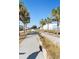 Street view with sidewalk and palm trees on a bright, sunny day. The street is bordered by lawns and businesses at 400 Dona Dr, Nokomis, FL 34275