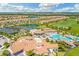 Aerial view of a community with a pool and clubhouse surrounded by tennis courts, golf course, and homes at 5529 Mulligan Way, Bradenton, FL 34211