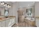 Bright bathroom featuring dual vanity sinks, tiled shower, and a corner tub by a window at 5529 Mulligan Way, Bradenton, FL 34211
