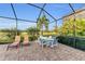 Screened patio with brick flooring, dining table, lounge chairs, and golf course view at 5529 Mulligan Way, Bradenton, FL 34211