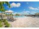 Community pool area with lounge chairs, umbrellas, and a rock waterfall feature under a sunny blue sky at 5529 Mulligan Way, Bradenton, FL 34211