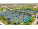 Aerial view of the tennis courts surrounded by palms and lush landscaping in a vibrant community setting at 5529 Mulligan Way, Bradenton, FL 34211