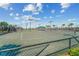 Well-maintained tennis courts surrounded by lush landscaping and palm trees under a sunny, partly cloudy sky at 5529 Mulligan Way, Bradenton, FL 34211