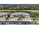 Aerial view of tan condos with garages, a lake, and a lush golf course in the background at 6326 Grand Oak Cir # 101, Bradenton, FL 34203