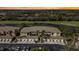 Sunset aerial view of tan condos with garages, a lake, and a lush golf course in the background at 6326 Grand Oak Cir # 101, Bradenton, FL 34203