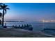 Scenic waterfront view at dusk, featuring palm trees, a pier, and a distant city skyline at 679 Norsota Way, Sarasota, FL 34242