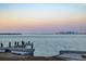 Scenic waterfront view featuring a weathered pier and a skyline in the distance at sunrise at 679 Norsota Way, Sarasota, FL 34242