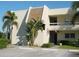 Low-rise condo with a mix of stucco and wood facade, parking lot, and tropical landscaping at 7211 W Country Club N Dr # 135, Sarasota, FL 34243