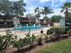 Community pool with lounge chairs surrounded by lush greenery and tropical palm trees at 805 Spring Lakes Blvd # 805, Bradenton, FL 34210
