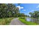 Scenic walking path with mature trees winds along a tranquil pond and lush landscaping at 8513 Golden Dawn Ct, Sarasota, FL 34241