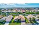 Aerial view of a home with lush landscaping, a brick driveway, and a two-car garage in a waterfront community under a blue sky at 104 Inlets Blvd # 104, Nokomis, FL 34275