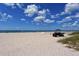 Wide sandy beach with a utility vehicle parked near the shore under a clear blue sky at 104 Inlets Blvd # 104, Nokomis, FL 34275