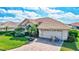 Attractive home boasting a brick driveway, lush landscaping, two-car garage, and bicycles parked outside under a bright blue sky at 104 Inlets Blvd # 104, Nokomis, FL 34275