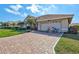 View of the front of a home with an attached garage, paver driveway, and manicured landscaping at 104 Inlets Blvd # 104, Nokomis, FL 34275