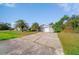 Exterior view of the home, featuring tropical landscaping and a concrete driveway leading to a two-car garage at 1124 Ample Ave, Port Charlotte, FL 33948