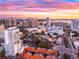 Aerial view of a city featuring a modern building, waterfront, and a colorful sunset backdrop at 1335 2Nd St # 402, Sarasota, FL 34236