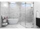 Bright bathroom featuring a soaking tub, a glass-enclosed shower, and marble tiling at 1335 2Nd St # 402, Sarasota, FL 34236